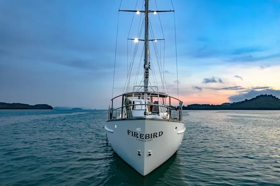 The sailing yacht FIREBIRD at anchor at dusk, seen from the bow
