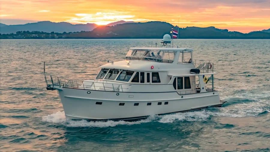 A motor yacht flying the Thai flag, under way at sunset