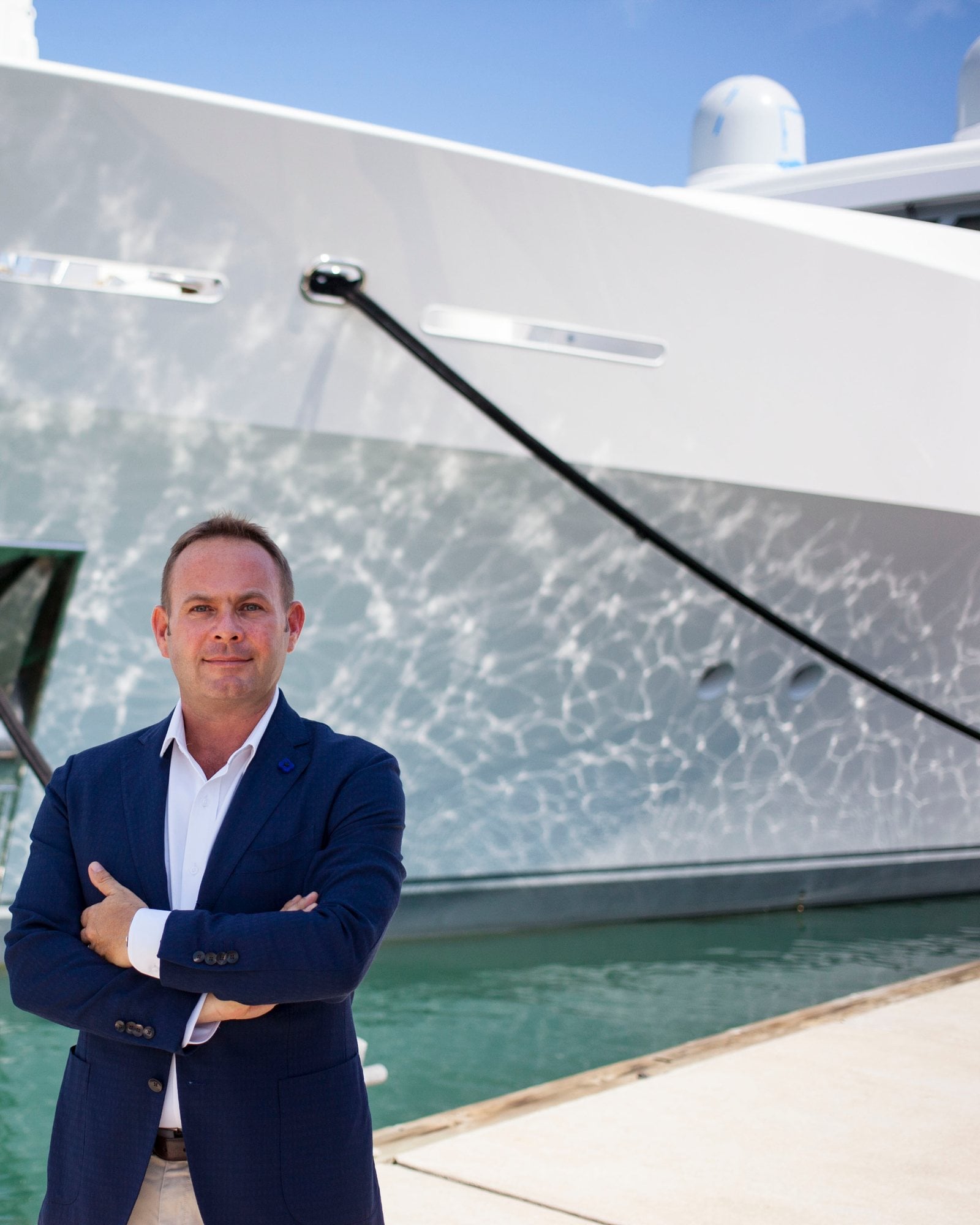 Martin Holmes standing on the quay in front of the bow of a large motor yacht